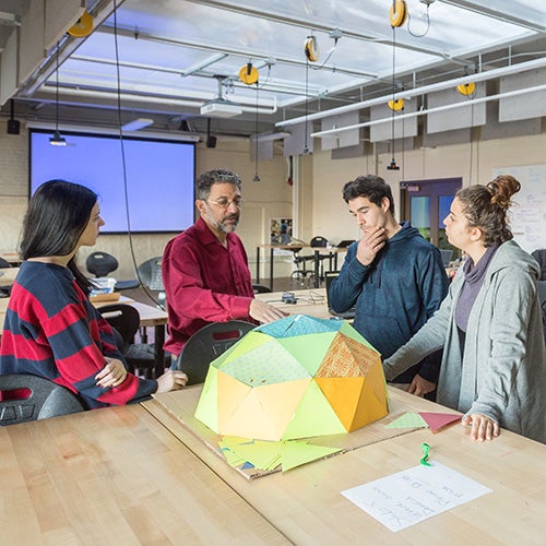 Architecture professor works with three students on a structure prototype