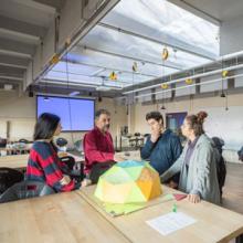 Students and professor review a 3d model of a design