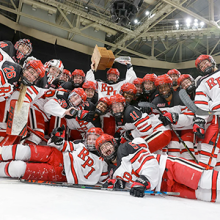 Women's ice hockey team poses after a big win