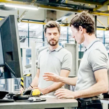 Two students look at a computer screen of mechanical drawings