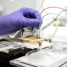 Gloved hand works with wires on a circuit board