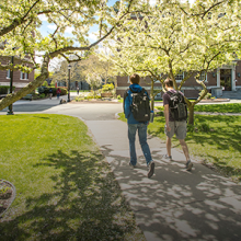 Two students walking across campus in the spring