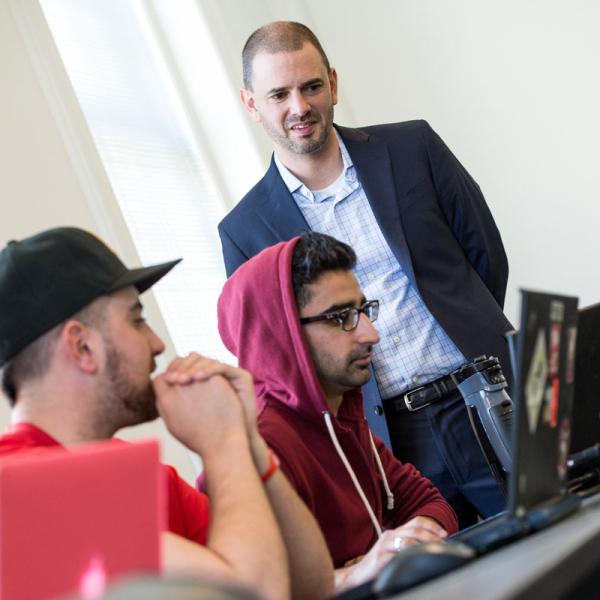 Lally professor watches two students working at a laptop